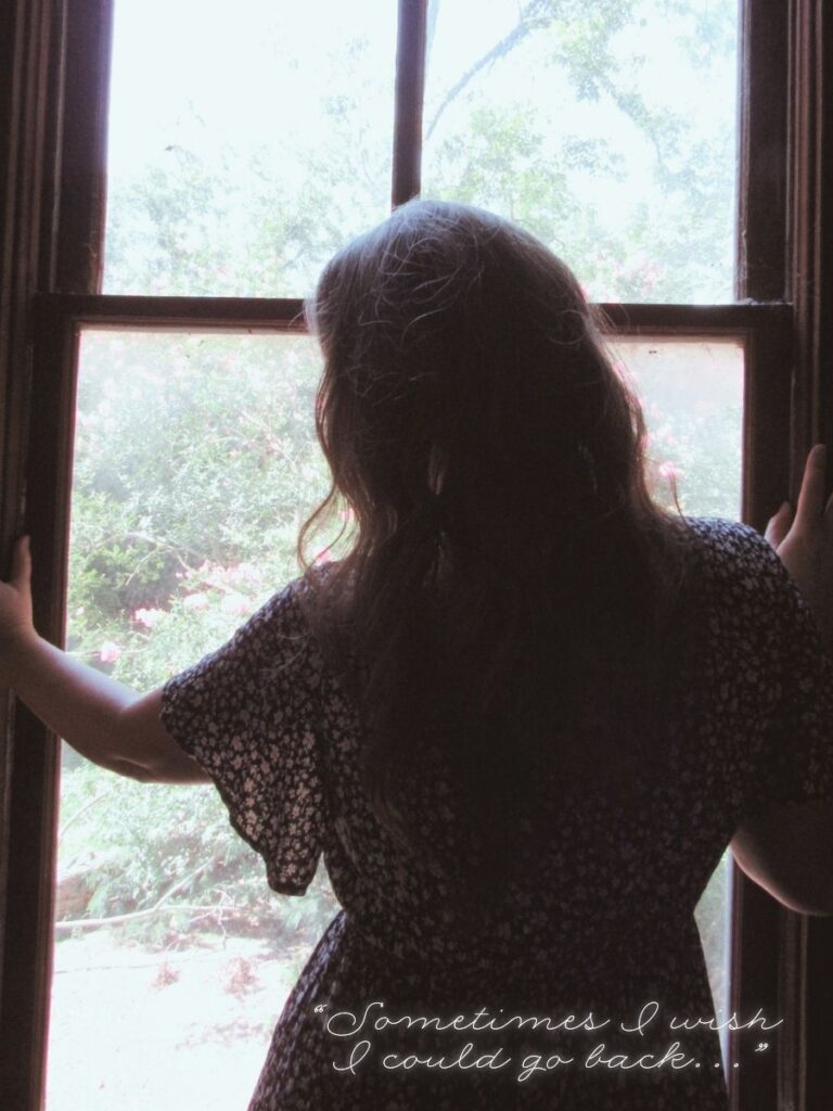 woman standing in the window of an old house